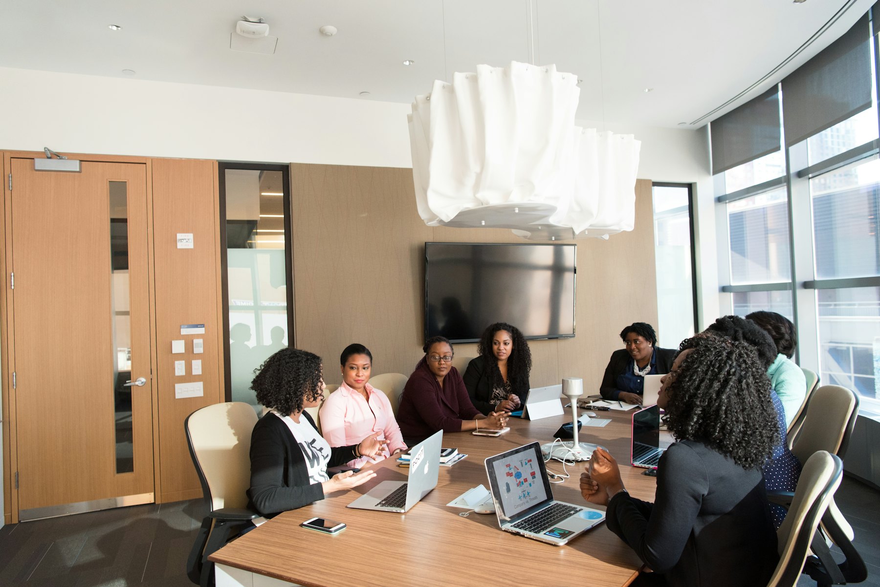 A team meeting around a boardroom table with laptops